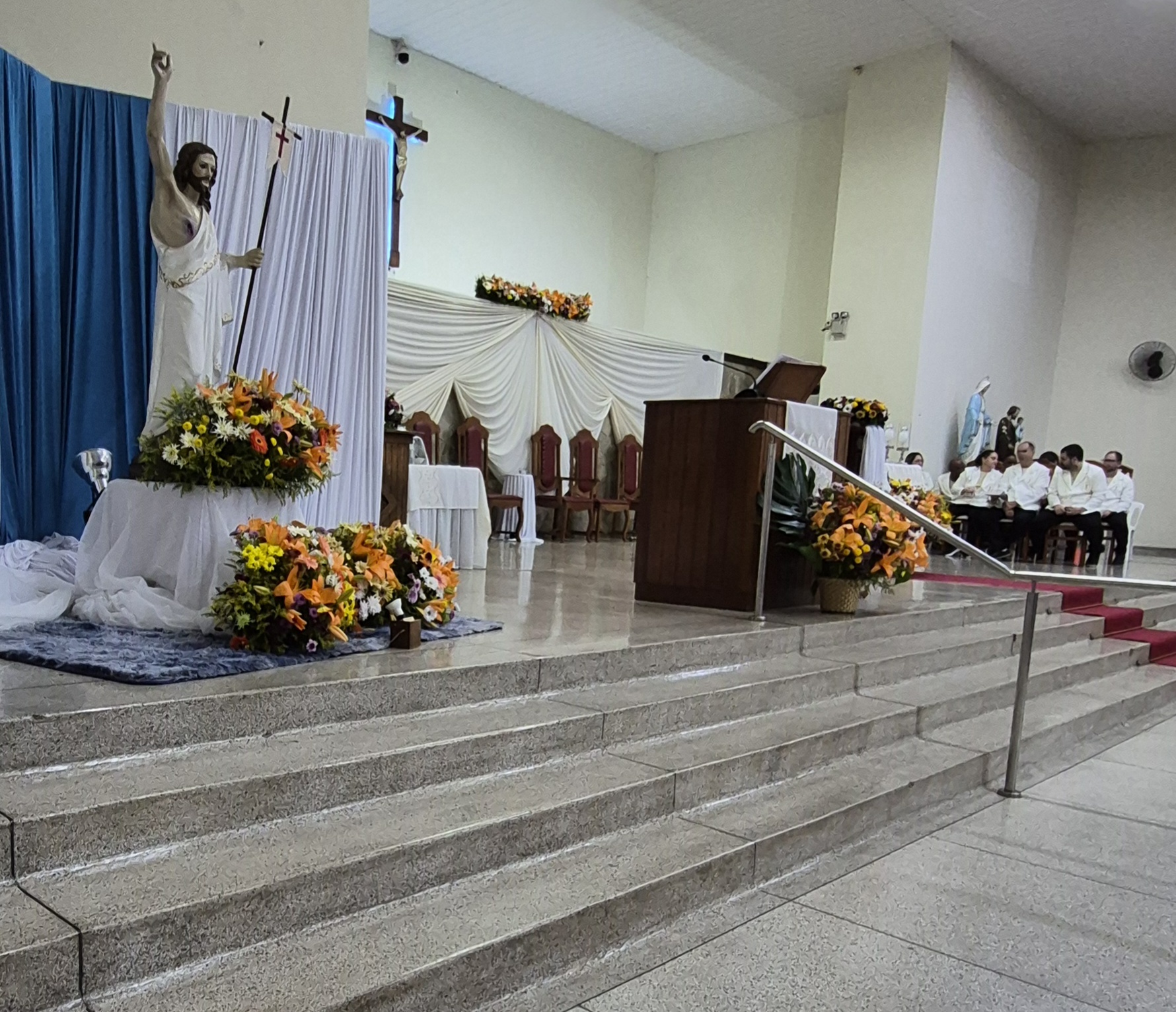 Imagem de Cristo Ressuscitado ornamentada com flores no presbitério
